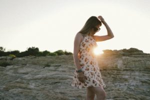 woman in white and red floral sleeveless dress standing on seashore during daytime