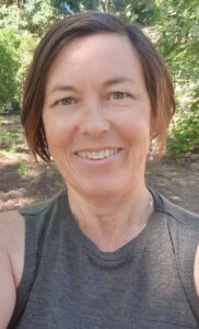 Woman smiling with green shrubs in the background