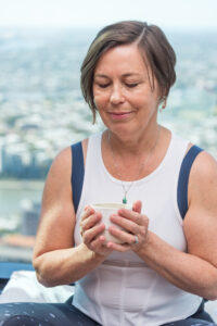 A woman looking relaxed with eyes closed holding a cup of tea