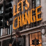 a woman walking past a building with a sign that says let's change